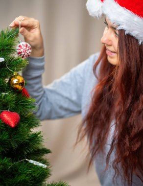 Öğleden sonra kadın yılbaşı ağacını süslüyor.