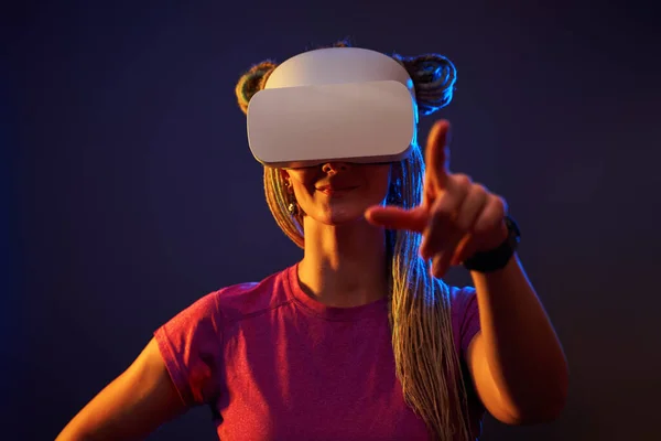 Vrouw gebruikt virtual reality headset. Neon licht studio portret. — Stockfoto