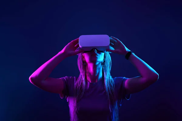 La mujer está usando auriculares de realidad virtual. Retrato de estudio de luz de neón. —  Fotos de Stock