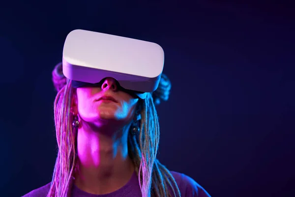 Frau benutzt Virtual-Reality-Headset. Neonlicht-Studioporträt. — Stockfoto