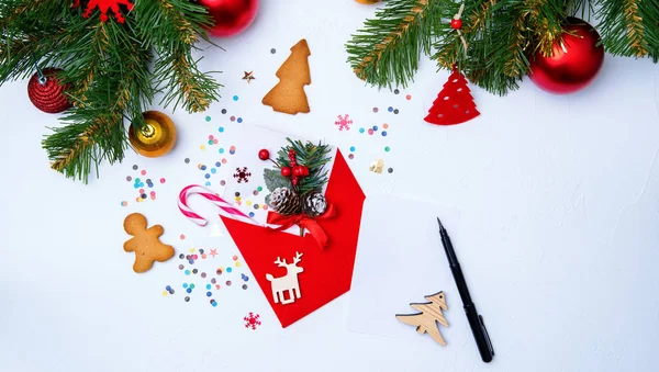 Foto von rotem Umschlag, Plätzchen, Zweigen von Fichtenweihnachtsdekoration auf weißem Hintergrund — Stockfoto