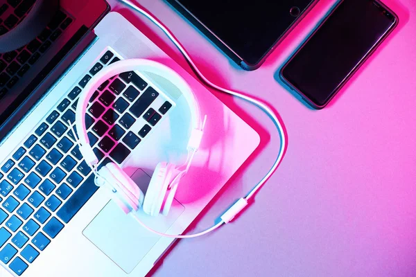 Laptop dengan headphone, tablet dan telepon di atas meja dengan warna neon modern . — Stok Foto