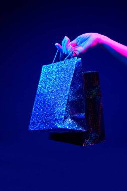 Neon renkli alışveriş torbaları olan kadın elleri.