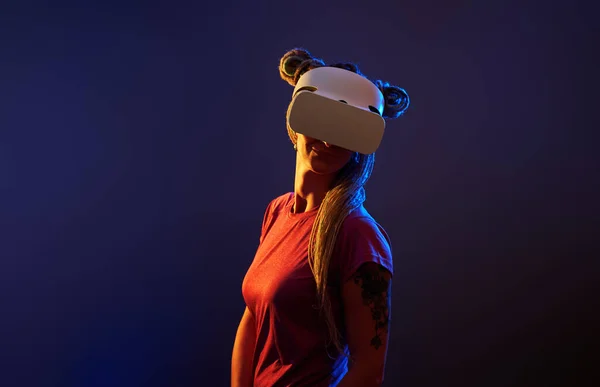 Woman is using virtual reality headset. Neon light studio portrait.