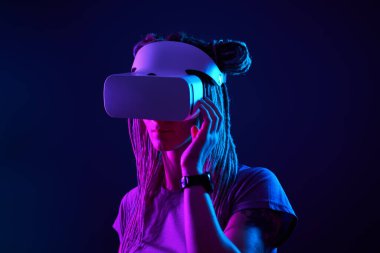 Kadın sanal gerçeklik kulaklığı kullanıyor. Neon Light Stüdyo Portresi.