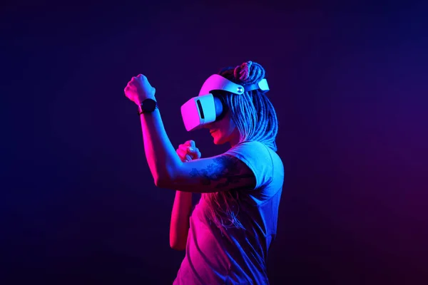 La mujer está usando auriculares de realidad virtual. Retrato de estudio de luz de neón. — Foto de Stock