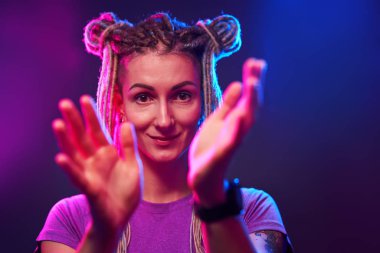 Mutlu kız neon ışıkta kameraya bakıyor.