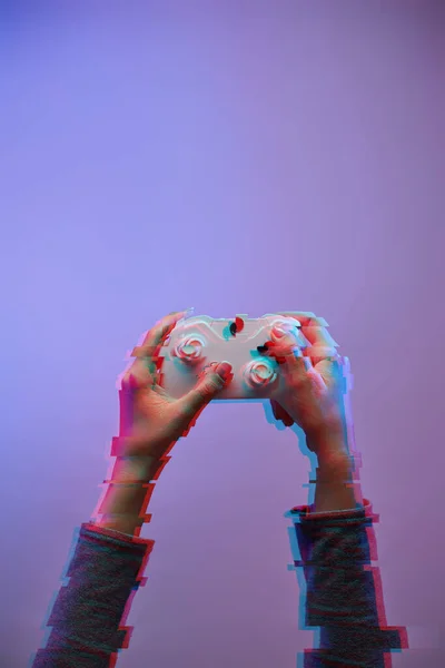Vrouwelijke handen met een spel joystick op violette achtergrond. — Stockfoto