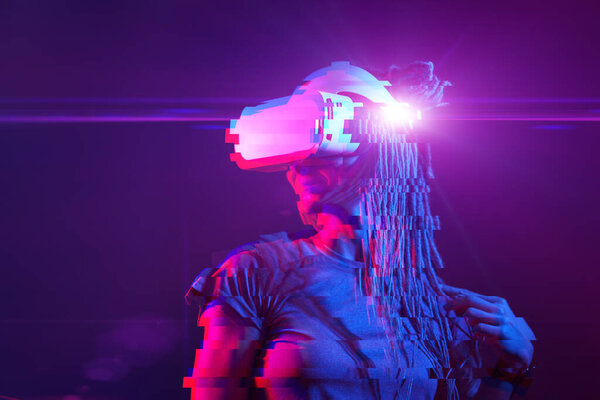 Woman is using virtual reality headset. Neon light studio portrait. Image with glitch effect.