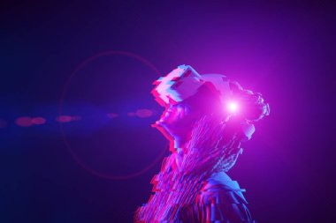 Woman is using virtual reality headset. Neon light studio portrait. Image with glitch effect.