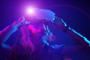 Woman is using virtual reality headset. Neon light studio portrait. Image with glitch effect.