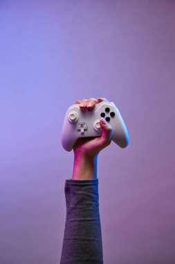 Mor arka planda beyaz gamepad ile el.