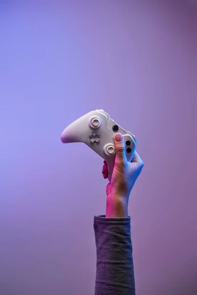 Mão com gamepad branco no fundo violeta . — Fotografia de Stock