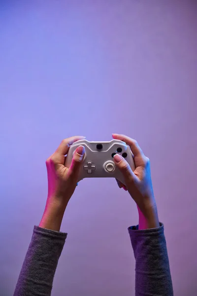 Mãos femininas com um joystick jogo no fundo violeta . — Fotografia de Stock