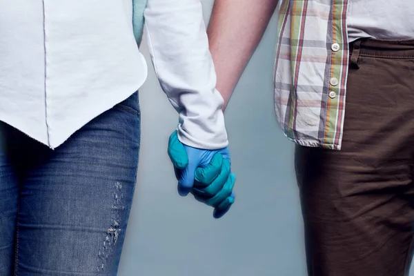 Hombre y mujer con guantes médicos tomados de la mano. Primer plano . — Foto de Stock