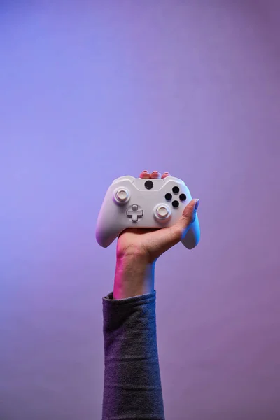 Mão com gamepad branco no fundo violeta . — Fotografia de Stock