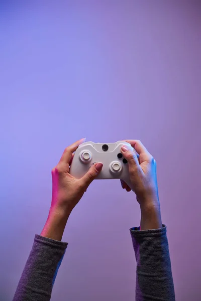 Kvinnliga händer med ett spel joystick på violett bakgrund. — Stockfoto