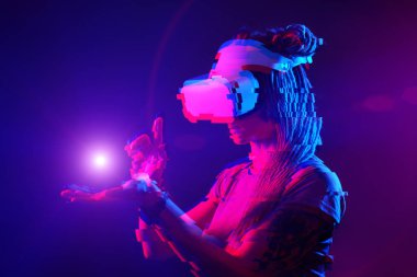 Woman is using virtual reality headset. Neon light studio portrait. Image with glitch effect.