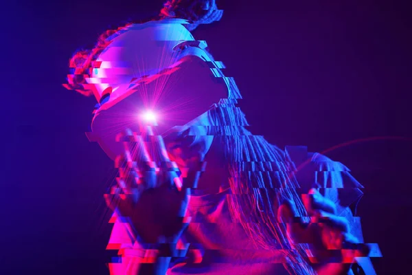 Woman is using virtual reality headset. Neon light studio portrait. Image with glitch effect. — Zdjęcie stockowe