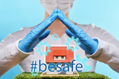 Woman in medical gloves and mask holds hands over a house. Concept of home stay, quarantine, security inside the house. clipart