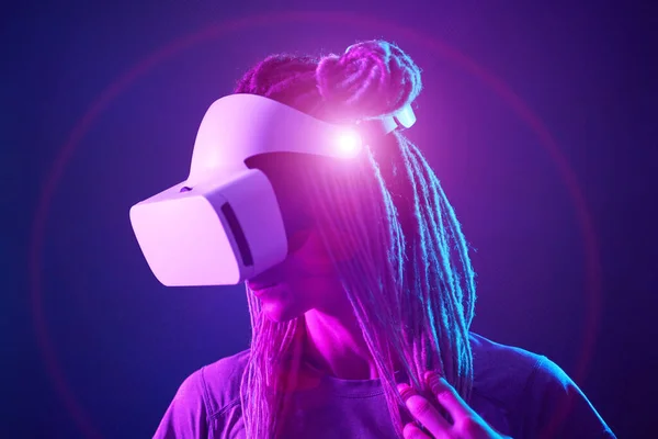 Vrouw gebruikt virtual reality headset. Neon licht studio portret. — Stockfoto