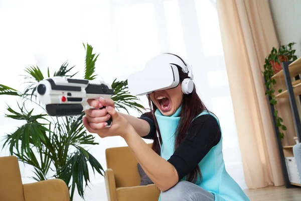 Kobieta z wirtualnej rzeczywistości słuchawki i blaster gra. — Zdjęcie stockowe