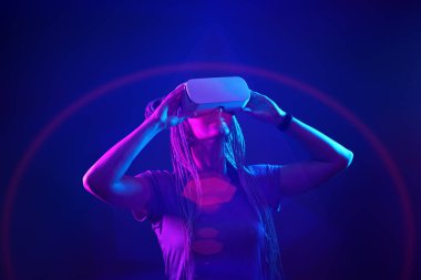 Kadın sanal gerçeklik kulaklığı kullanıyor. Neon Light Stüdyo Portresi.