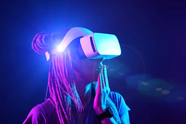 Woman is using virtual reality headset. Neon light studio portrait. — Stock Photo, Image