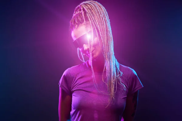 Young girl in sunglasses looking at camera in neon light — Stock Photo, Image