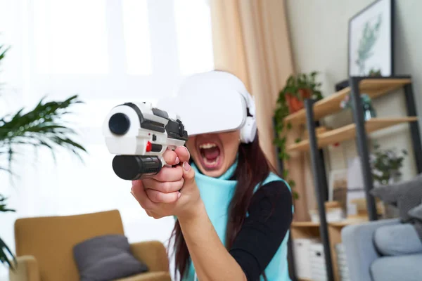 Vrouw met virtual reality headset en blaster speelt spel. — Stockfoto