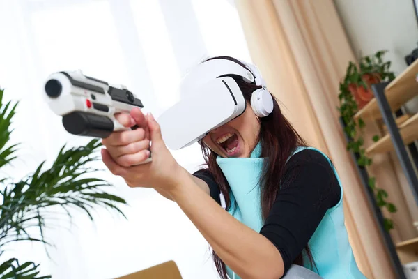 Kobieta z wirtualnej rzeczywistości słuchawki i blaster gra. — Zdjęcie stockowe