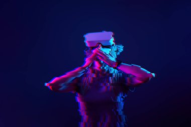 Woman is using virtual reality headset. Neon light studio portrait. Image with glitch effect.