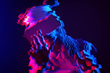 Woman is using virtual reality headset. Neon light studio portrait. Image with glitch effect.