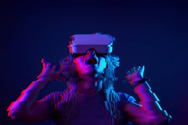 Woman is using virtual reality headset. Neon light studio portrait. Image with glitch effect.