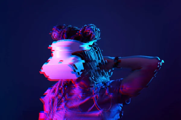 Woman is using virtual reality headset. Neon light studio portrait. Image with glitch effect. — Stockfoto