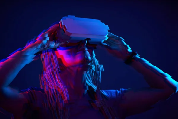 Woman is using virtual reality headset. Neon light studio portrait. Image with glitch effect. — Φωτογραφία Αρχείου