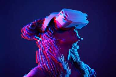 Woman is using virtual reality headset. Neon light studio portrait. Image with glitch effect.