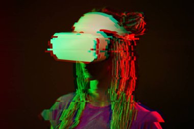 Woman is using virtual reality headset. Neon light studio portrait. Image with glitch effect.