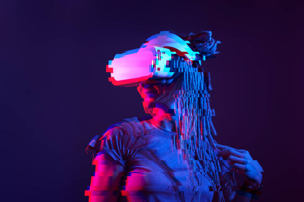 Woman is using virtual reality headset. Neon light studio portrait. Image with glitch effect.