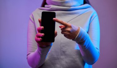 Esmer kız telefonu boş siyah ekranla tutuyor.