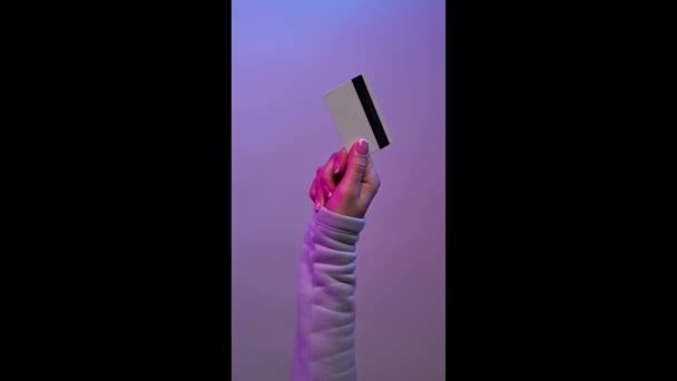 紫色の背景にクレジットカードを保持手。ボンバーアンズビデオ. — ストック動画