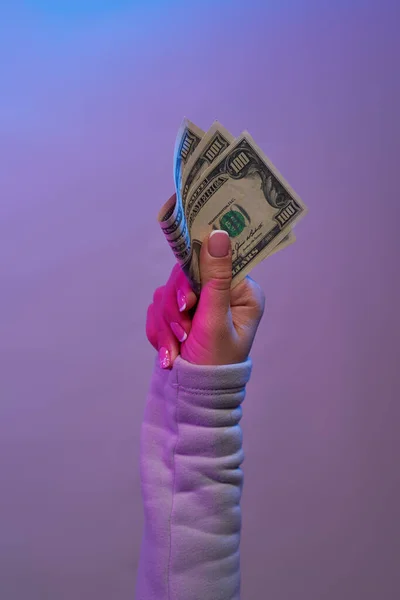 Hand holding banknotes on violet background.