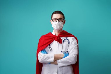 Süper kahraman peleriniyle cerrahi maske takan bir doktor..