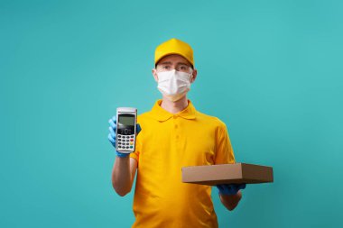 Yüzünde tıbbi maske olan kurye kutusunu ve iğnesini tutuyor..