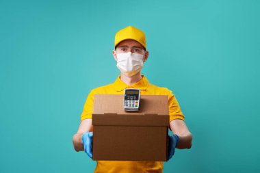 Yüzünde tıbbi maske olan kurye kutusunu ve iğnesini tutuyor..