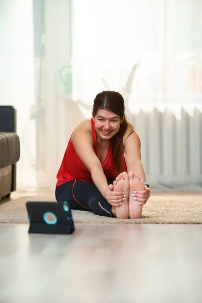 Frau macht Stretching, praktiziert Yoga-Übungen zu Hause mit Video-Tutorials. — Stockfoto