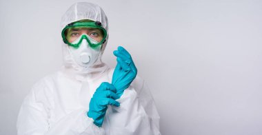 Doktor PPE giyiyor. Kostüm, eldiven ve cerrahi maske..