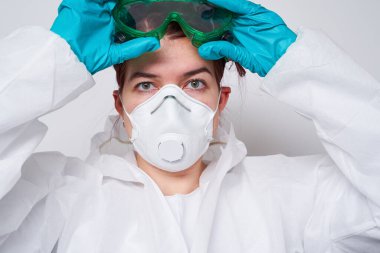 Doktor PPE giyiyor. Kostüm, eldiven ve cerrahi maske..