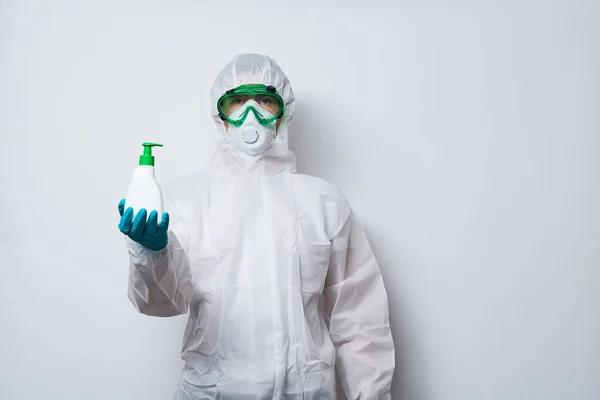 Le médecin porte un EPI costume, gants et masque chirurgical en cape de super-héros avec une bouteille de savon liquide antiseptique . — Photo