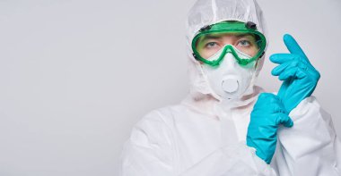 Doktor PPE giyiyor. Kostüm, eldiven ve cerrahi maske..